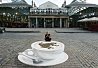 A young lady relaxes on the rim of a giant coffee cup in Covent Garden. The cup was created by pavement artist Manfred Stader to celebrate that from today every cup of coffee sold in Costa's UK stores will be made from beans sourced from Rainforest Alliance Certified farms.