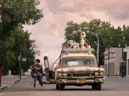 Mckenna Grace as Phoebe in the Ecto-1 jump seat with Finn Wolfhard as Trevor at the wheel in Ghostbusters: Afterlife, directed by Jason Reitman. Photo: Kimberley French. Copyright: 2019 CTMG, Inc. All Rights Reserved.