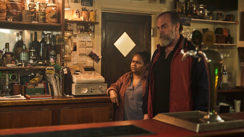 Ursula Yovich as Carol and Hugo Weaving as Billy in The Royal Hotel, directed by Kitty Green. Copyright: See Saw Films/Universal Studios. All Rights Reserved.