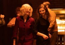 Anne Hathaway as Dr Rebecca St John and Thomas McKenzie as Eileen Dunlop in Eileen, directed by William Oldroyd. Photo: Jeong Park. Copyright: Universal Pictures. All Rights Reserved.