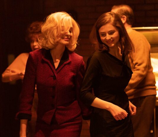 Anne Hathaway as Dr Rebecca St John and Thomas McKenzie as Eileen Dunlop in Eileen, directed by William Oldroyd. Photo: Jeong Park. Copyright: Universal Pictures. All Rights Reserved.