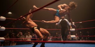 Zac Efron as Kevin Von Erich performing a flying kick in the ring in The Iron Claw, directed by Sean Durkin. Copyright: House Claw LLC. All Rights Reserved.