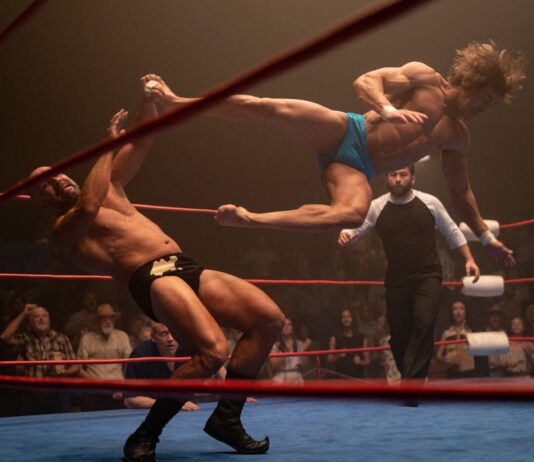 Zac Efron as Kevin Von Erich performing a flying kick in the ring in The Iron Claw, directed by Sean Durkin. Copyright: House Claw LLC. All Rights Reserved.