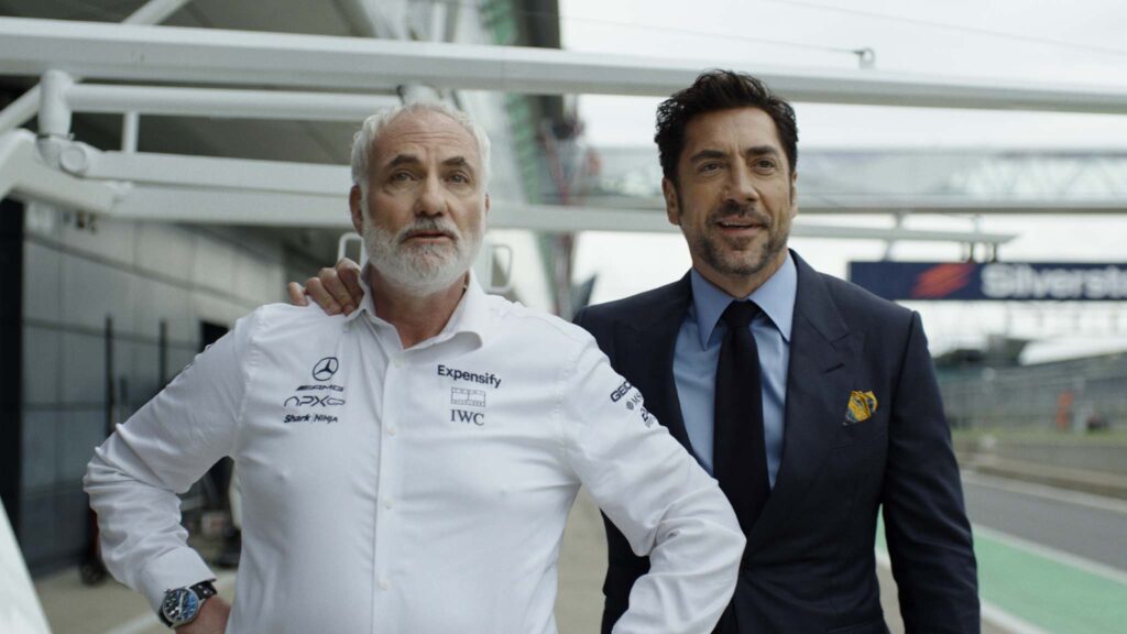 Kim Bodnia as Kaspar and Javier Bardem as Ruben Cervantes in F1: The Movie, directed by Joseph Kosinski. Copyright: Warner Bros. Entertainment Inc./Apple Original Films. All Rights Reserved.