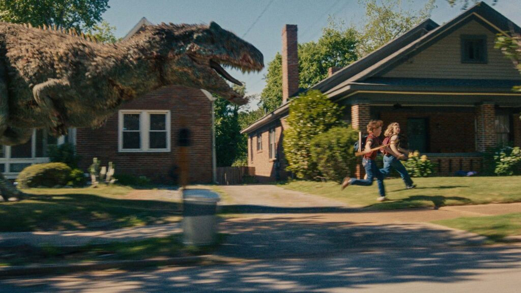 A dinosaur on the loose on Oak Street in The End Of Oak Street, directed by David Robert Mitchell. Photo: Daniel McFadden. Copyright: Warner Bros. Entertainment Inc. All Rights Reserved.