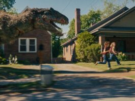A dinosaur on the loose on Oak Street in The End Of Oak Street, directed by David Robert Mitchell. Photo: Daniel McFadden. Copyright: Warner Bros. Entertainment Inc. All Rights Reserved.