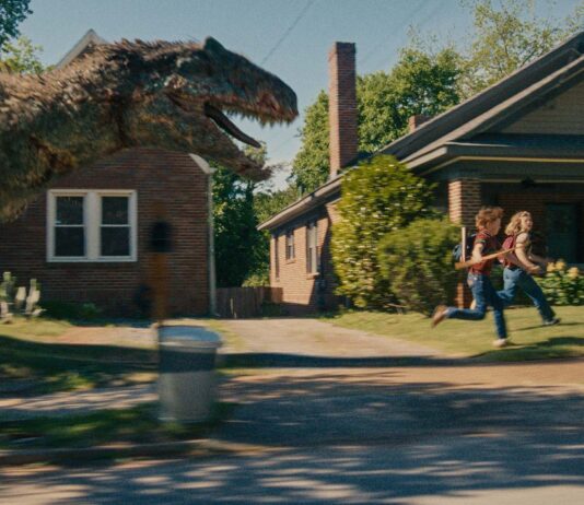 A dinosaur on the loose on Oak Street in The End Of Oak Street, directed by David Robert Mitchell. Photo: Daniel McFadden. Copyright: Warner Bros. Entertainment Inc. All Rights Reserved.