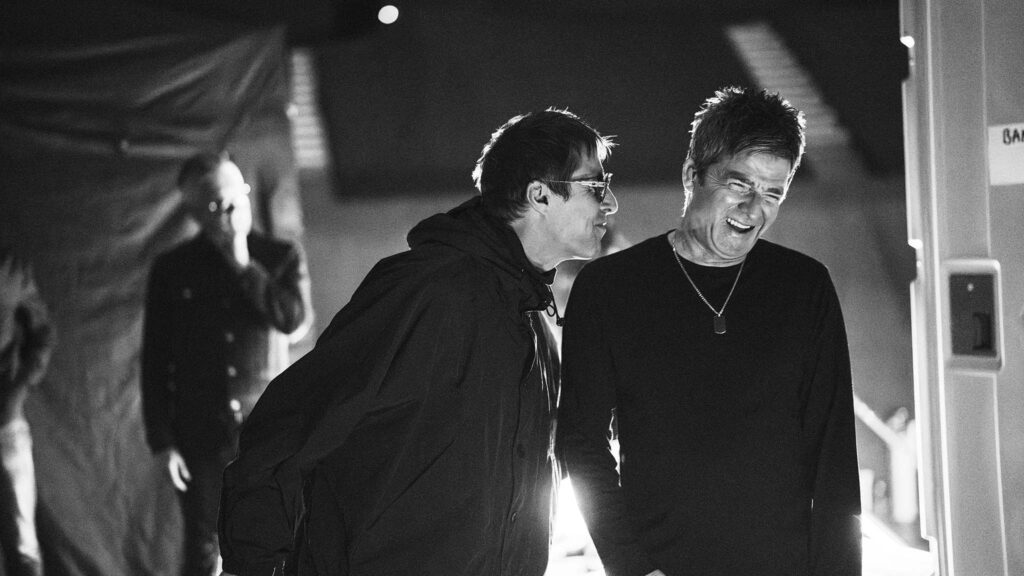 Liam Gallagher and Noel Gallagher backstage laughing in Oasis: Don’t Look Back In Anger, directed by Will Lovelace and Dylan Southern. Copyright: Simon Emmett. All Rights Reserved.